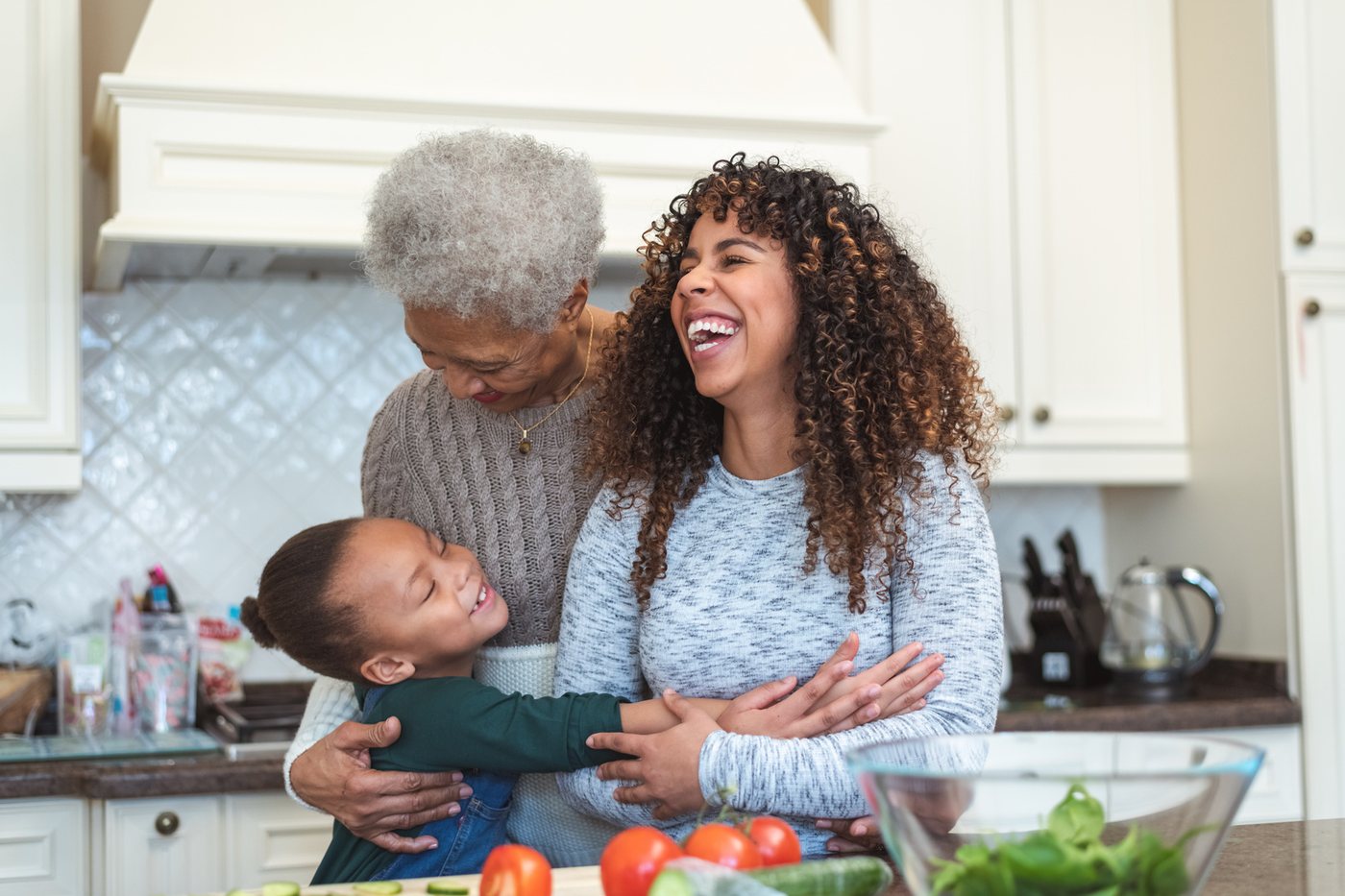 Grandmother, mother and young child laughing while cooking together