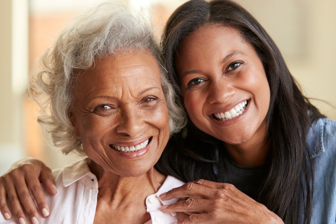 Older woman and her adult daughter smiling cheek to cheek